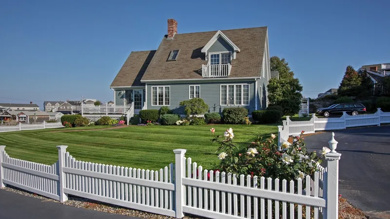 Blue gray Cape style home with a white picket fence in Maine